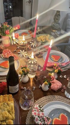 a table is set with plates, cups and candles for a valentine's day dinner