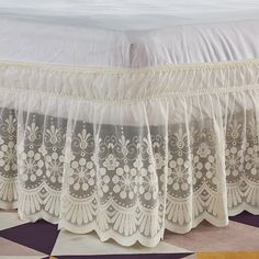 the bed is made with white lace on it's edges and has a purple checkered floor