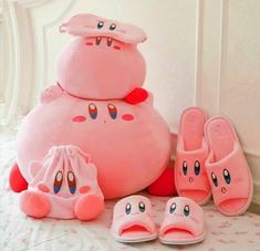 a pink stuffed animal sitting on top of a bed next to slippers