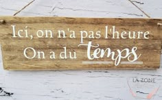 a wooden sign hanging on the side of a building that says, ici on na pas l'heure on au du tempes