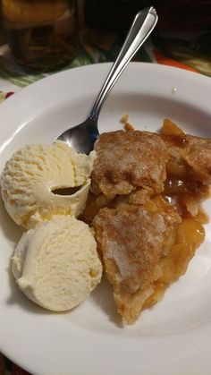 a piece of pie and ice cream on a white plate with a spoon in it