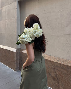 In the vibrant summer aesthetic of city streets, a woman in the perfect summer day out  flowing green dress tosses a bouquet of white flowers over her shoulder. Urban chic with natural elegance
#outfitinspo #summerlook Perfect Summer Day, Aesthetic Flower, Vacation Style, Urban Chic, City Streets, Summer Looks