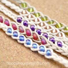 three braided bracelets with multicolored beads on top of each other, sitting on a brown surface