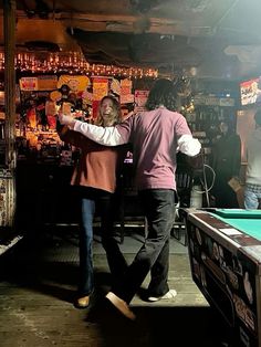 two people are playing pool in a bar