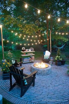 an outdoor fire pit with lights strung over it and some chairs around the firepit