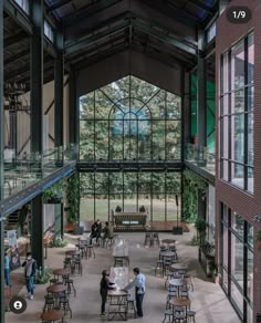 the inside of a building with people walking around and tables in front of them,