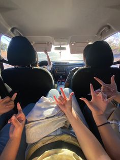 people sitting in the back seat of a car with their hands up