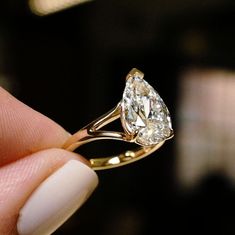 a close up of a person's hand holding a ring with a diamond on it