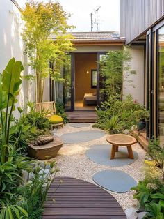 an outdoor garden with wooden benches, plants and graveled path leading to the front door