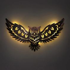 an owl shaped wall light with yellow lights on it's back and wings spread out