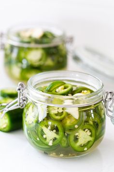 pickled jalapenos sitting in a glass jar on a white counter top