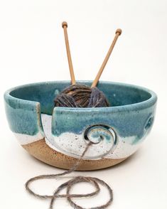 a bowl with yarn and knitting needles in it