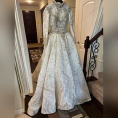 a wedding dress is displayed on a mannequin in front of a doorway with white curtains