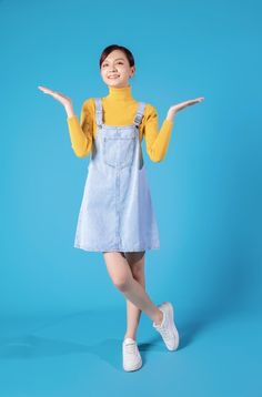 a young woman is posing with her hands out in front of the camera while wearing an overall dress