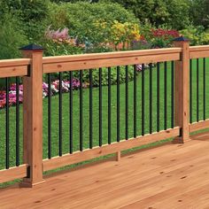 a wooden deck with black iron railing and flowerbeds in the backgroud