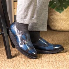 a man in grey pants and black shoes standing next to a chair with his foot on the ground