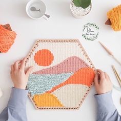 someone is working on a colorful rug with yarn and crochet hooks next to it