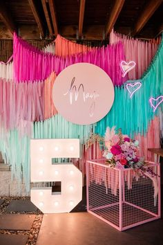 a room with pink, blue and green streamers hanging from the ceiling next to a number six sign