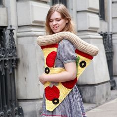 a woman is walking down the street carrying a large piece of crocheted material