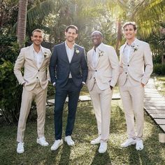 three men in suits and white shoes standing next to each other with palm trees behind them