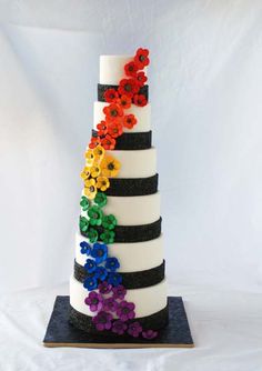 a multi - tiered cake decorated with flowers and black stripes is on display against a white backdrop