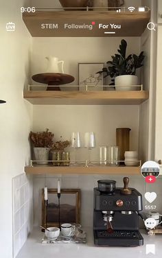 a coffee maker sitting on top of a counter next to shelves filled with cups and saucers