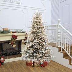 a white christmas tree in front of a fireplace with stockings on the mantels