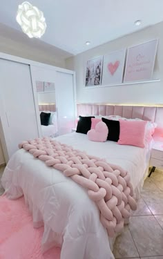 a bed with pink and black pillows on top of it