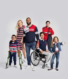 a man in a wheel chair with two children and an adult standing behind him, all wearing sweaters