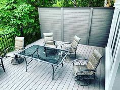 a glass table and chairs on a wooden deck