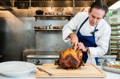 a man in an industrial kitchen slicing a turkey