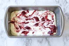 a cake pan filled with white frosting and cranberry toppings on top of a marble counter