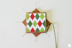 an ornament made out of brown paper with green and red squares