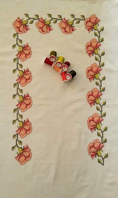 three rolls of thread sitting on top of a white tablecloth with pink flowers and green leaves