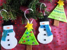 three snowman ornaments hanging from a christmas tree