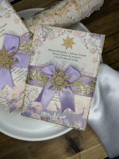 two cards with purple ribbons on them sitting on a plate next to a piece of bread