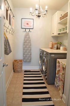 a washer and dryer in a small room next to a door with pictures on the wall