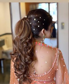 the back of a woman's head with long, wavy hair and beads on it