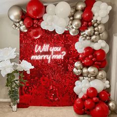 a red and silver party backdrop with balloons