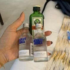 two bottles of vodka sitting next to each other in front of a woman's hand