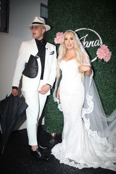 a man and woman dressed up in wedding attire standing next to each other with an umbrella