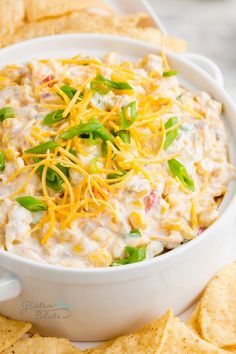 a white bowl filled with dip surrounded by tortilla chips