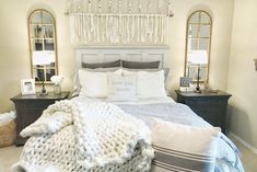 a bed with pillows and blankets on top of it next to two mirrors in a bedroom