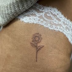 a woman's stomach with a small sunflower tattoo on her lower back side