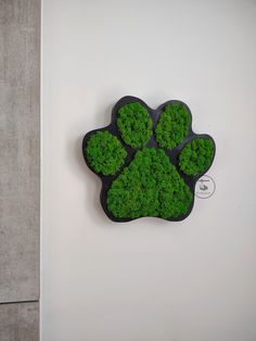 a dog's paw made out of moss is displayed on the wall next to a toilet