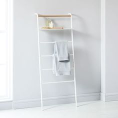 a white ladder leaning against a wall with towels on it