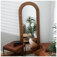 a mirror sitting on top of a wooden table next to a chair and potted plant