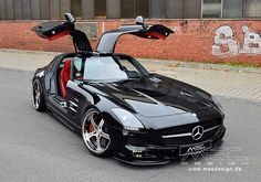 a black mercedes sls parked on the side of the road with its doors open