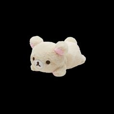 a small white teddy bear laying on top of a black background