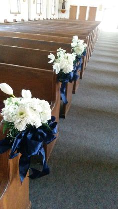 flowers are placed on the pews in this church wedding ceremony aisle arrangement, with blue ribbon and white carnations